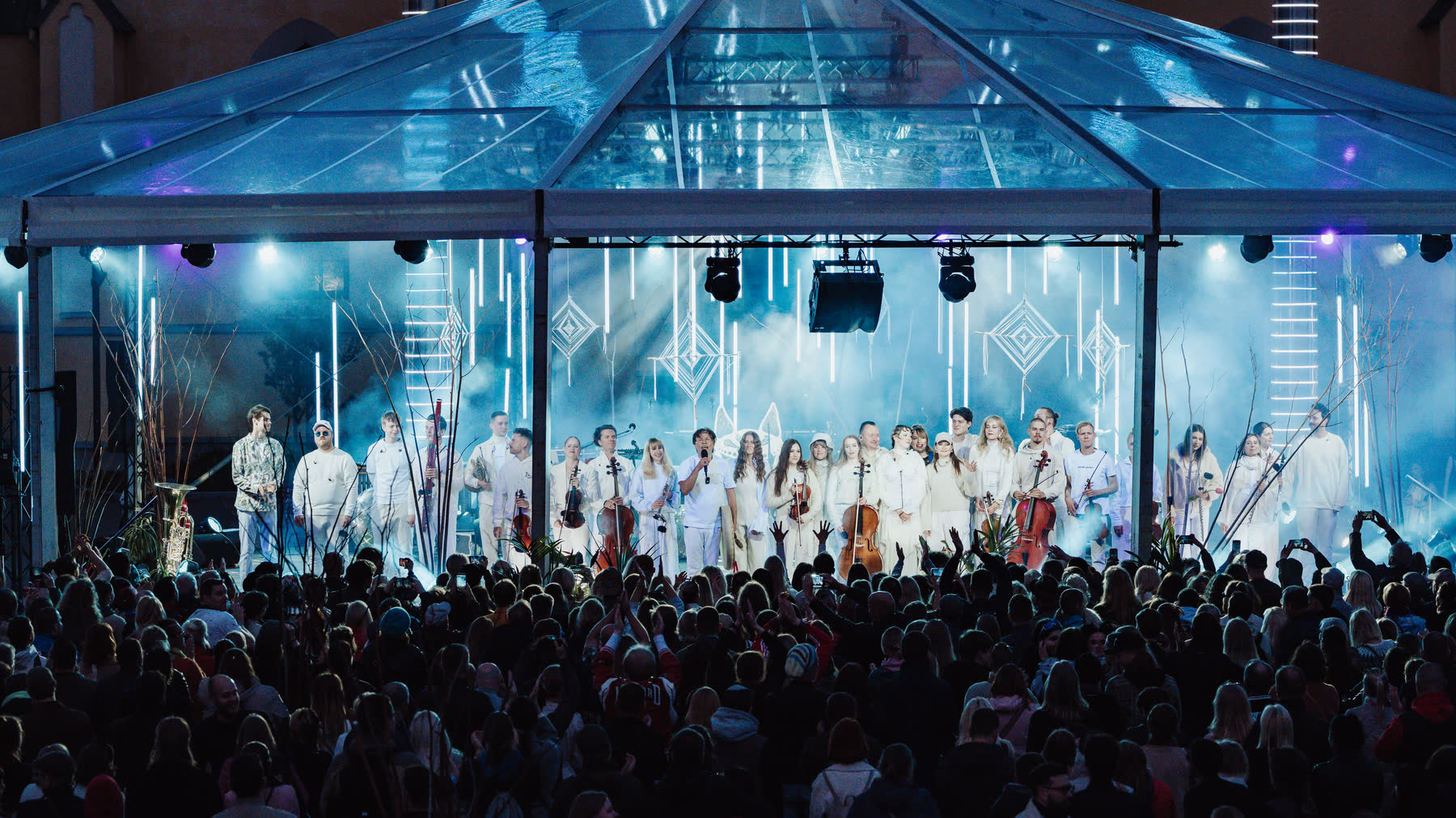 Nordic Pulse on an outdoor stage under a glass canopy, the full ensemble in white in front of a large crowd.